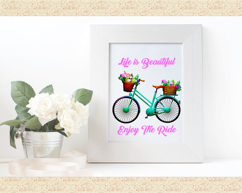 May include: A teal bicycle with a basket of flowers on the handlebars and another basket of flowers on the back rack. The bicycle is on a white background with the text "Life is Beautiful" and "Enjoy The Ride" in pink.