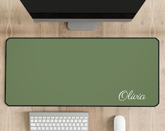 May include: A green desk mat with a white border and the name "Olivia" printed in white on the bottom right corner. A white keyboard and a white mouse are on the desk.
