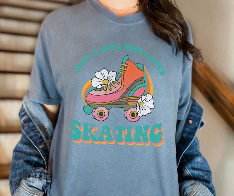 May include: A blue t-shirt with a retro graphic of a roller skate with flowers and the text "Just a girl who loves skating".
