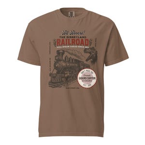 May include: Brown t-shirt featuring a vintage-style graphic of a steam train on tracks. The design includes the text "All Aboard! The Disneyland Railroad" and "Don't Miss the Grand Canyon Diorama Est. 1958."