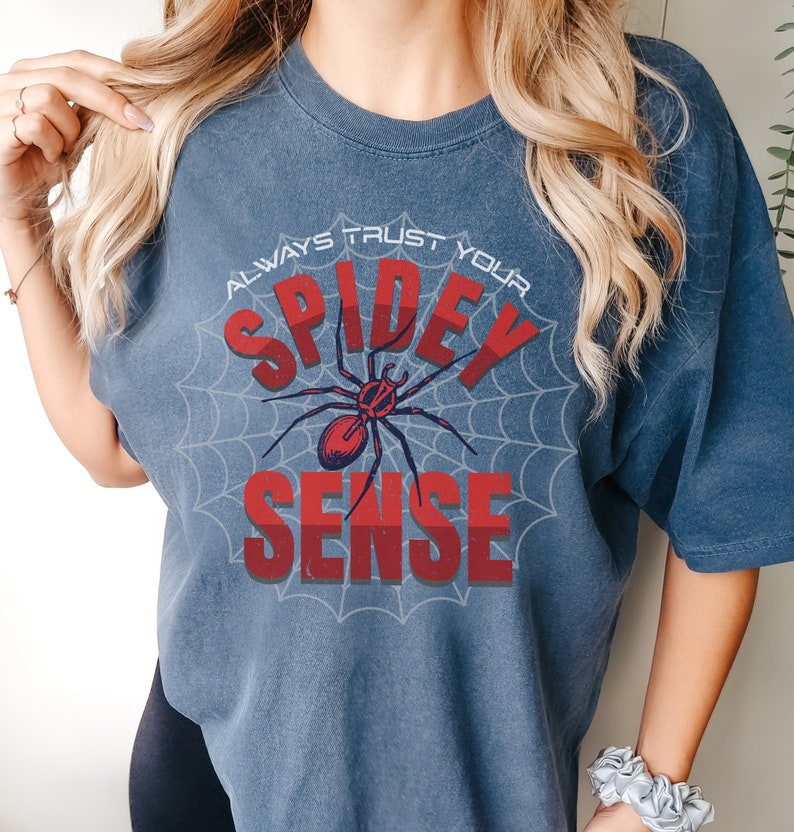 May include: A blue t-shirt with a spider web design and the text "Always Trust Your Spidey Sense" in red and white lettering.