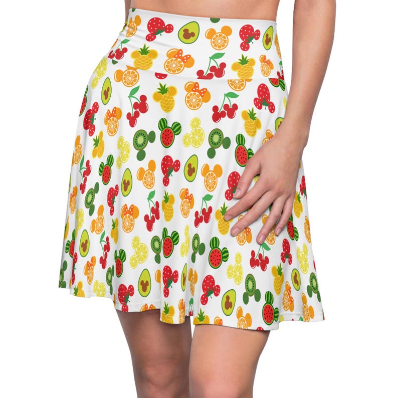 May include: A white skater skirt with a colorful fruit and Mickey Mouse head print. The print features cherries, pineapples, kiwis, oranges, avocados, and watermelons.