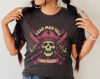 Op de afbeelding: Een donkergrijs T-shirt met een schedel en gekruiste beenderen afbeelding. De afbeelding toont een piraten schedel met een rode hoed en de tekst "Dead Men Tell No Tales".
