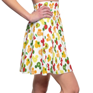 May include: A white skater skirt with a colorful fruit and Mickey Mouse head print. The skirt features a variety of fruits including strawberries, lemons, pineapples, watermelon, kiwi, and avocados.