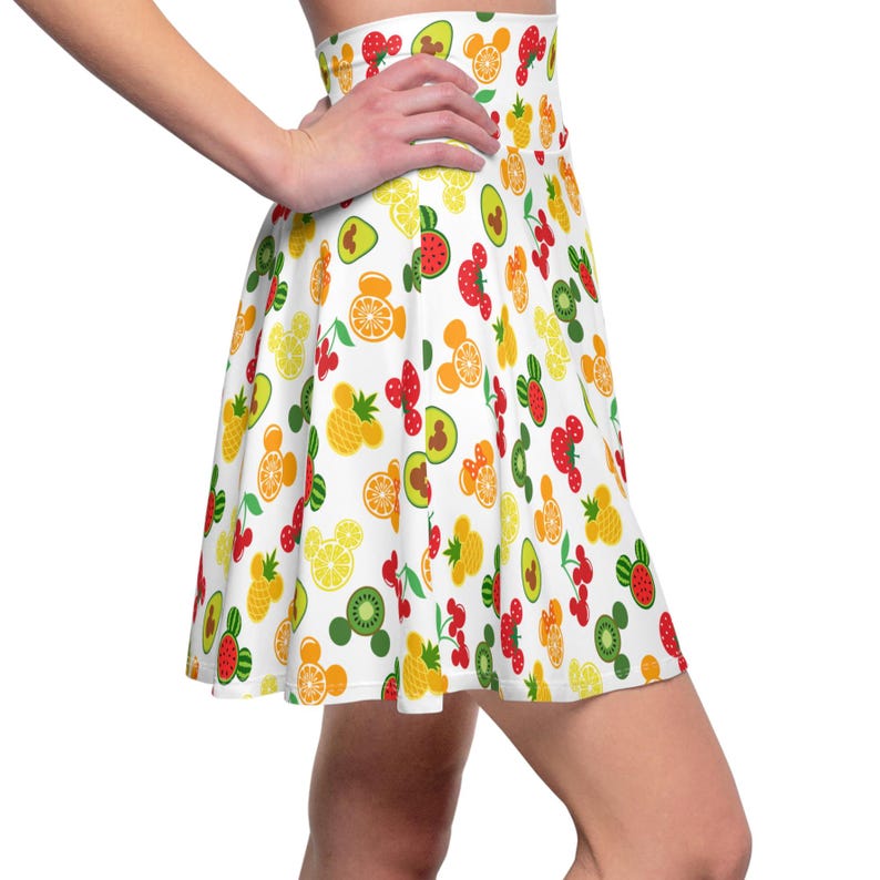 May include: A white skater skirt with a colorful fruit and Mickey Mouse head print. The skirt features a variety of fruits including strawberries, lemons, pineapples, watermelon, kiwi, and avocados.