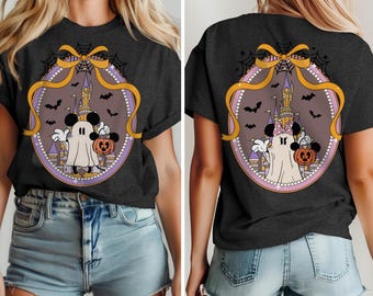 Könnte beinhalten: Dunkelgraues T-Shirt mit einem Halloween-Motiv. Das Design zeigt einen Cartoon-Geist, einen Kürbis und ein Schloss, alles in einem ovalen Rahmen mit einer Schleife und Spinnweben. Das T-Shirt hat kurze Ärmel.