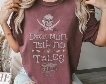 Op de afbeelding: Een maronkleurig T-shirt met een witte grafische print van een schedel met gekruiste beenderen, een kompas en een schatkist. De tekst op het shirt luidt "Dead Men Tell No Tales".
