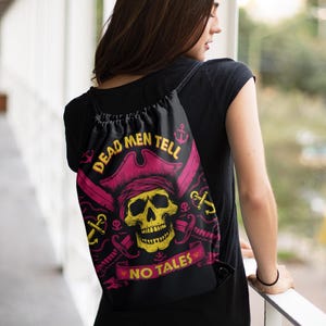 Może przedstawiać: Czarny plecak ze sznurkiem ze wzorem czaszki pirata. Żółta czaszka nosi różowy kapelusz, ze skrzyżowanymi mieczami. Tekst "DEAD MEN TELL NO TALES" znajduje się nad czaszką, z kotwicami i banerem.