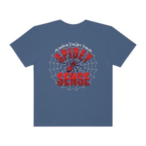 May include: A blue t-shirt with a white spider web design and the text "Always Trust Your Spidey Sense" in red.