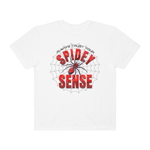 May include: White t-shirt with a red spider graphic and the text "Always Trust Your Spidey Sense" in a white spiderweb.