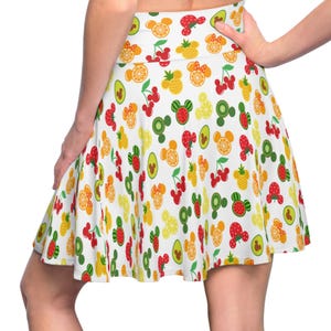 May include: A white skirt with a colorful fruit and Mickey Mouse head pattern. The skirt has a flared silhouette and a high waist.