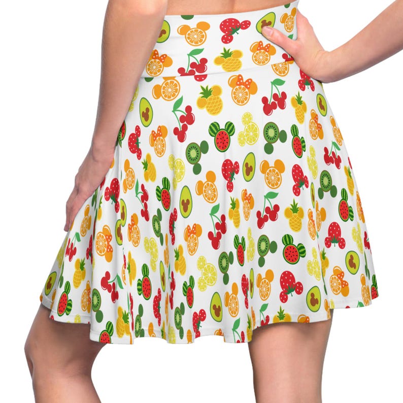May include: A white skirt with a colorful fruit and Mickey Mouse head pattern. The skirt has a flared silhouette and a high waist.