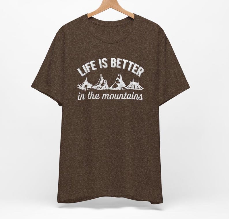May include: A brown t-shirt with the text "Life is better in the mountains" and a graphic of mountain peaks.