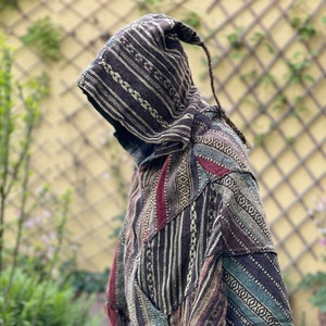 Peut inclure: Un poncho à capuche brun et noir avec une bordure en franges. Le poncho est fait d'un tissu tissé avec un motif géométrique.
