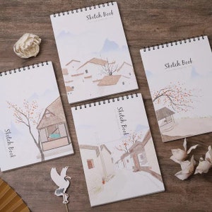 May include: Four spiral bound sketchbooks with watercolour illustrations of houses and trees. Each sketchbook has the text "Sketch Book" printed on the cover.
