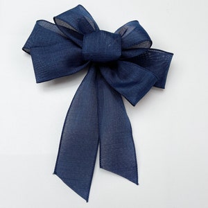 May include: A navy blue sheer ribbon bow with a long tail.