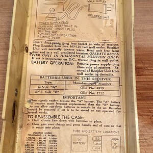 K&ouml;nnte beinhalten: Vintage Emerson Radio Modell 569 A.C.-D.C. Radiokomponenten. Das Innere des Radiogeh&auml;uses zeigt gedruckte Anweisungen, Diagramme sowie Batterie- und R&ouml;hrenstandorte. Das Geh&auml;use ist cremefarben.