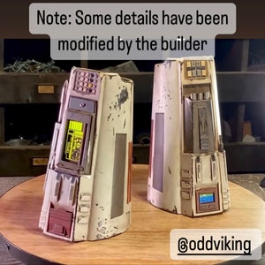 May include: Two white, weathered, detailed, sci-fi prop models with various buttons, lights, and panels. The models are on a wooden surface. Note: Some details have been modified by the builder. @oddviking