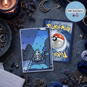Può includere: Uno schema a punto croce che raffigura un paesaggio blu pixelato con una figura centrale, mostrato accanto a una carta collezionabile Pokemon. L'immagine include un'etichetta circolare con il testo PDF Pattern e un'icona di controller.