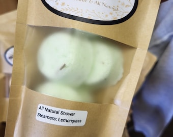 May include: A brown paper bag with a clear window, containing several light green shower steamers. The bag has a label that reads "Beauty Bee Soaps, Handmade & All Natural." A smaller label states "All Natural Shower Steamers: Lemongrass."