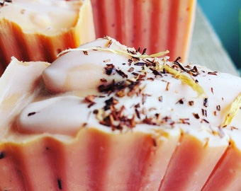 May include: Three handmade soap bars in a light pink color with a white swirl on top. The soap bars are decorated with brown and gold flecks.