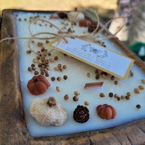 May include: A wooden tray with a white candle embedded with dried fruit, spices, and a small tag that reads "Handcrafted All Natural Soy Candle & Handpoured on Etsy".