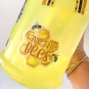 May include: A yellow reusable water bottle with a sticker that says "Save the Bees" with a honeycomb design and two bees.