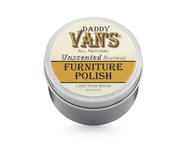 May include: A round, silver tin of Daddy Van's All Natural Unscented Beeswax Furniture Polish. The label features the brand name in a stylized font, with the words "Furniture Polish" in a gold banner. The tin contains 6 ounces of product.