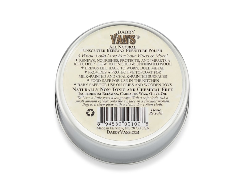 May include: A round, silver-colored tin of Daddy Van's Unscented Beeswax Furniture Polish. The label features text describing the product's benefits, including renewing and protecting wood surfaces. The product is made in Fairview, NC, USA.