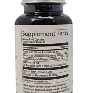 Puede incluir: Una botella de suplemento marr&oacute;n oscuro con tapa plateada. La etiqueta muestra "Supplement Facts" y enumera vitaminas y minerales, incluyendo vitamina C, D, calcio y magnesio. La botella contiene 60 porciones, con una porci&oacute;n de 2 c&aacute;psulas.