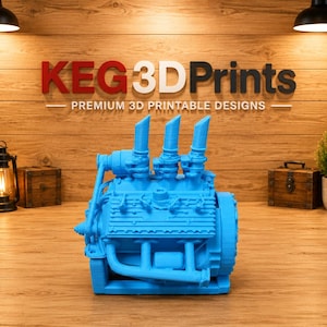 May include: A bright blue 3D printed model of a V8 engine block featuring three vertical exhaust stacks, detailed intake manifolds, and a side-mounted alternator. The engine model is displayed against a wooden wall with the text KEG 3D Prints.