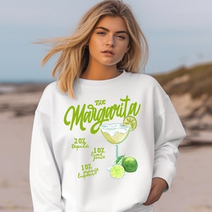 May include: White sweatshirt with a green graphic of a margarita cocktail and the text "THE Margarita" with the ingredients listed: 2 oz tequila, 1 oz lime juice, 1 oz orange liqueur.