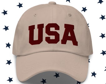 May include: A beige baseball cap with a red embroidered "USA" on the front.