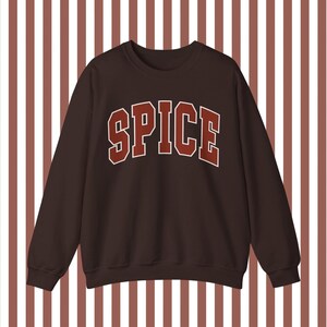 May include: A brown sweatshirt with the word "SPICE" printed in red on the front.
