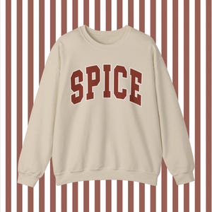 May include: A beige sweatshirt with a red "SPICE" graphic printed on the front.
