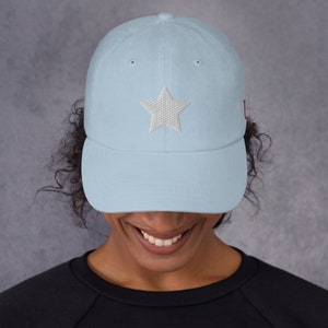 Pode incluir: Um bon&eacute; de beisebol azul claro com uma estrela branca bordada na frente e um "U" vermelho bordado na lateral.