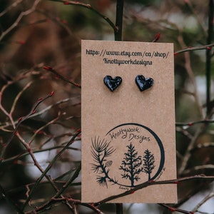 Puede incluir: Un par de pendientes de corazón negro en una tarjeta marrón con el texto "https://www.etsy.com/ca/shop/KnottyworkDesigns" y un logotipo de tres árboles con el texto "Knottywork Designs".