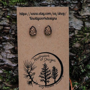 K&ouml;nnte beinhalten: Ein Paar Holz-Kiefernzapfen-Ohrringe auf einer braunen Karte mit dem Text "Knottywork Designs" und der Website-Adresse "https://www.etsy.com/ca/shop/Knottyworkdesigns".
