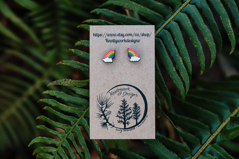 Pu&ograve; includere: Un paio di orecchini arcobaleno e nuvola su una carta marrone con il testo "https://www.etsy.com/ca/shop/Knottyworkdesigns".