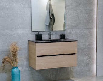 May include: A light wood bathroom vanity with two drawers and a black countertop. The vanity has a black rectangular sink and a chrome faucet. There are two black soap dispensers on the countertop.