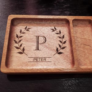 May include: A wooden tray with two compartments. The larger compartment has a laurel wreath design with the letter "P" and the name "PETER" engraved in the center.