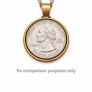 A gold-colored necklace with a round United States quarter dollar coin pendant hanging from it.