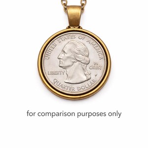 A gold-colored necklace with a round United States quarter dollar coin pendant hanging from it.