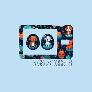 May include: A set of three phone decals featuring a space-themed pattern with cartoon dogs and planets. The text "3 Gals Decals" is printed below the decals.