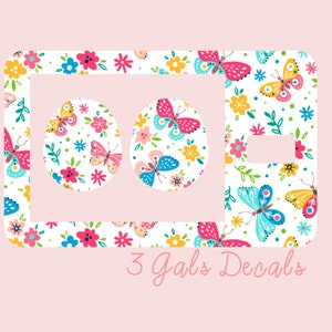 May include: A white background with a white outline of a phone with two circles in the middle. The phone and circles are filled with a pattern of colorful butterflies and flowers. The text "3 Gals Decals" is below the phone.