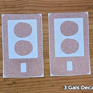 May include: Two pink glitter phone decals with two circles cut out. The decals are for covering electrical outlets. The text "3 Gals Decals" is at the bottom of the image.