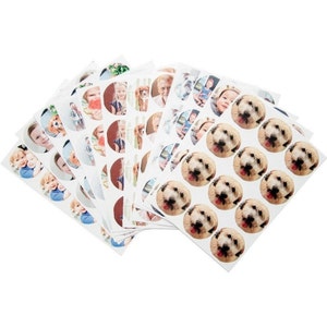 May include: A sheet of white paper with round stickers featuring various photos of people and dogs. The stickers are arranged in rows and columns.