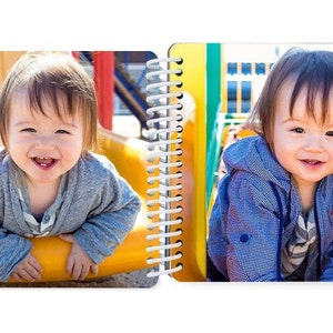 May include: Two toddlers smiling at the camera. One is on a yellow slide and the other is on a green and yellow playground structure.