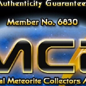 May include: A black and blue graphic logo for the International Meteorite Collectors Association, featuring the bold text IMCA, the phrase Authenticity Guaranteed, and Member No. 6830, accompanied by a stylized orange and white lightning bolt icon.