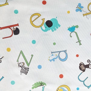 May include: White fabric with a colourful alphabet pattern featuring animals such as elephants, penguins, monkeys, and turtles. The letters are in various colours and styles, with some letters having a bold outline.